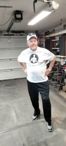 Fitness Coach Will Levin in t-shirt with logo hands on hips in home gym