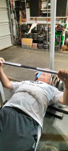 Fitness Coach Will Levin bench pressing in home gym